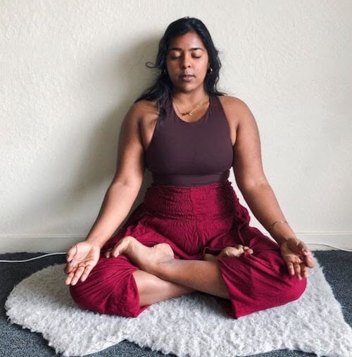 Divya Bala, yoga teacher, seated in her own, ancestral practice in Sukhasana (Easy Pose)