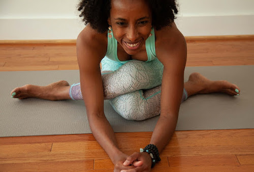 Zainab Zakari, yoga teacher, learning forward in Gomukhasana (Cow Face Pose)