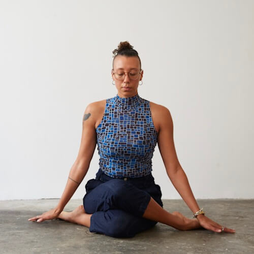 Europa Grace, yoga and meditation instructor, seated in Gomukhasana (Cow Face Pose, and meditating