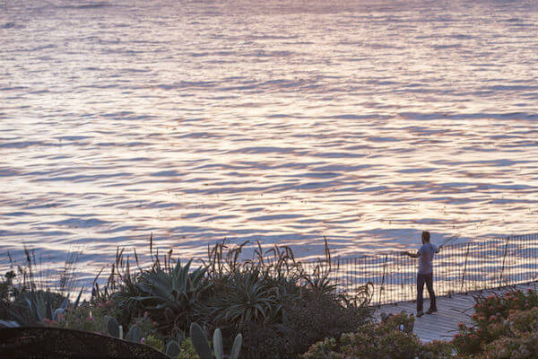 A man dances facing the Pacific Ocean on the pool deck at Esalen.